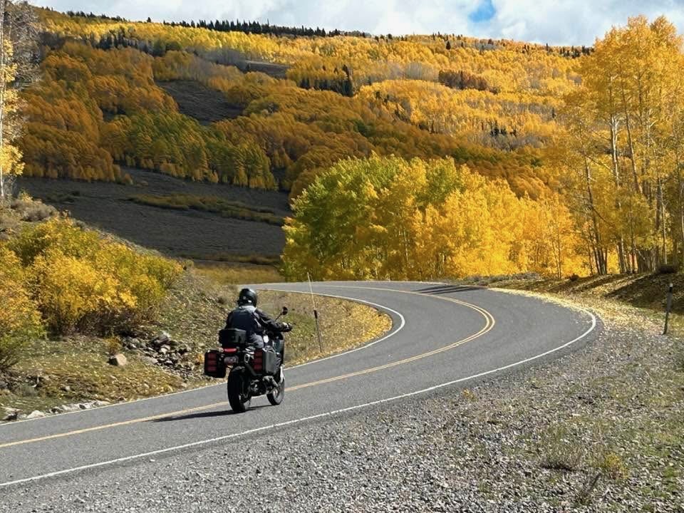 Rider on mountain road through golden aspens Colorado